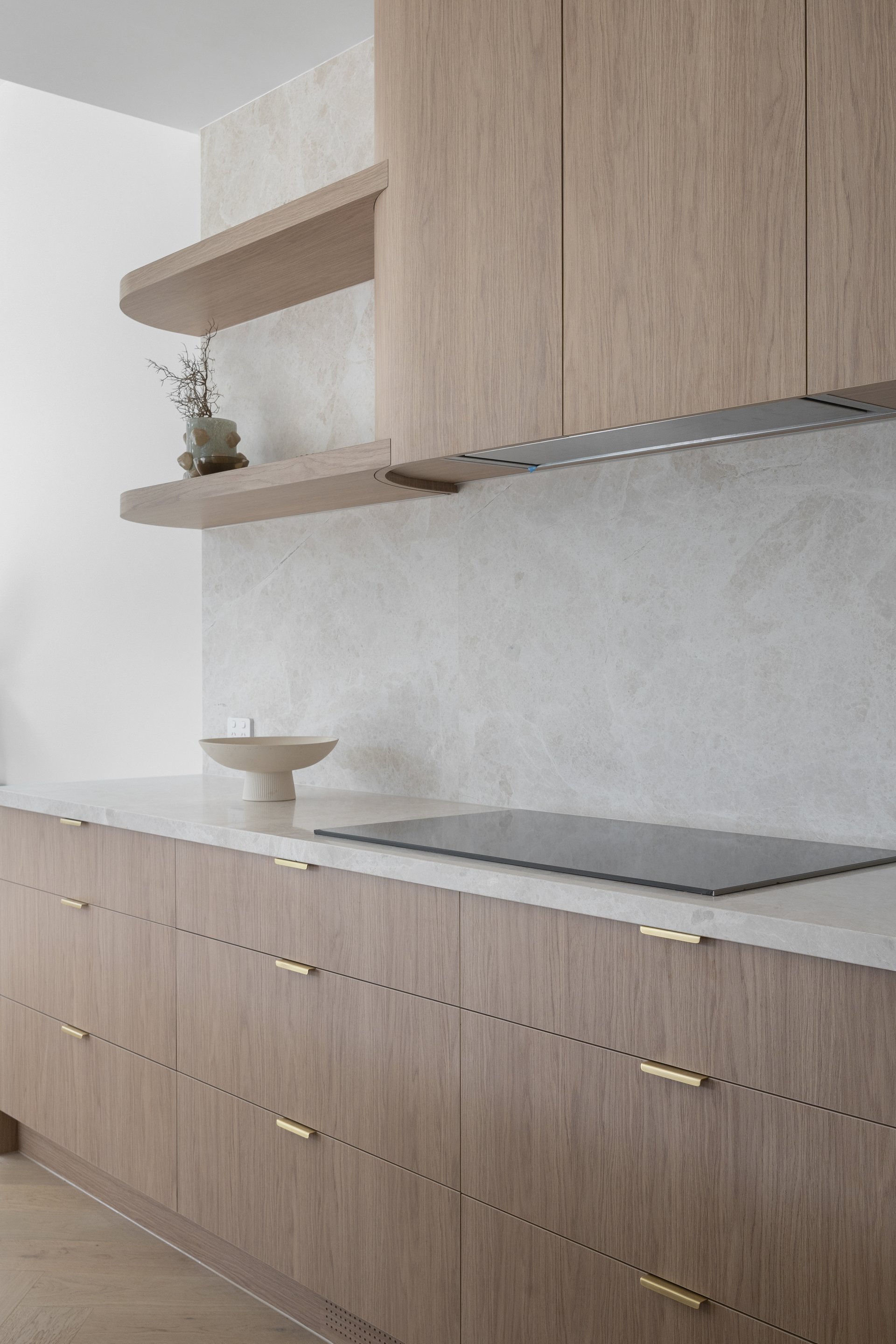 Cooktop, stone benchtop and timber cabinetry in the kitchen