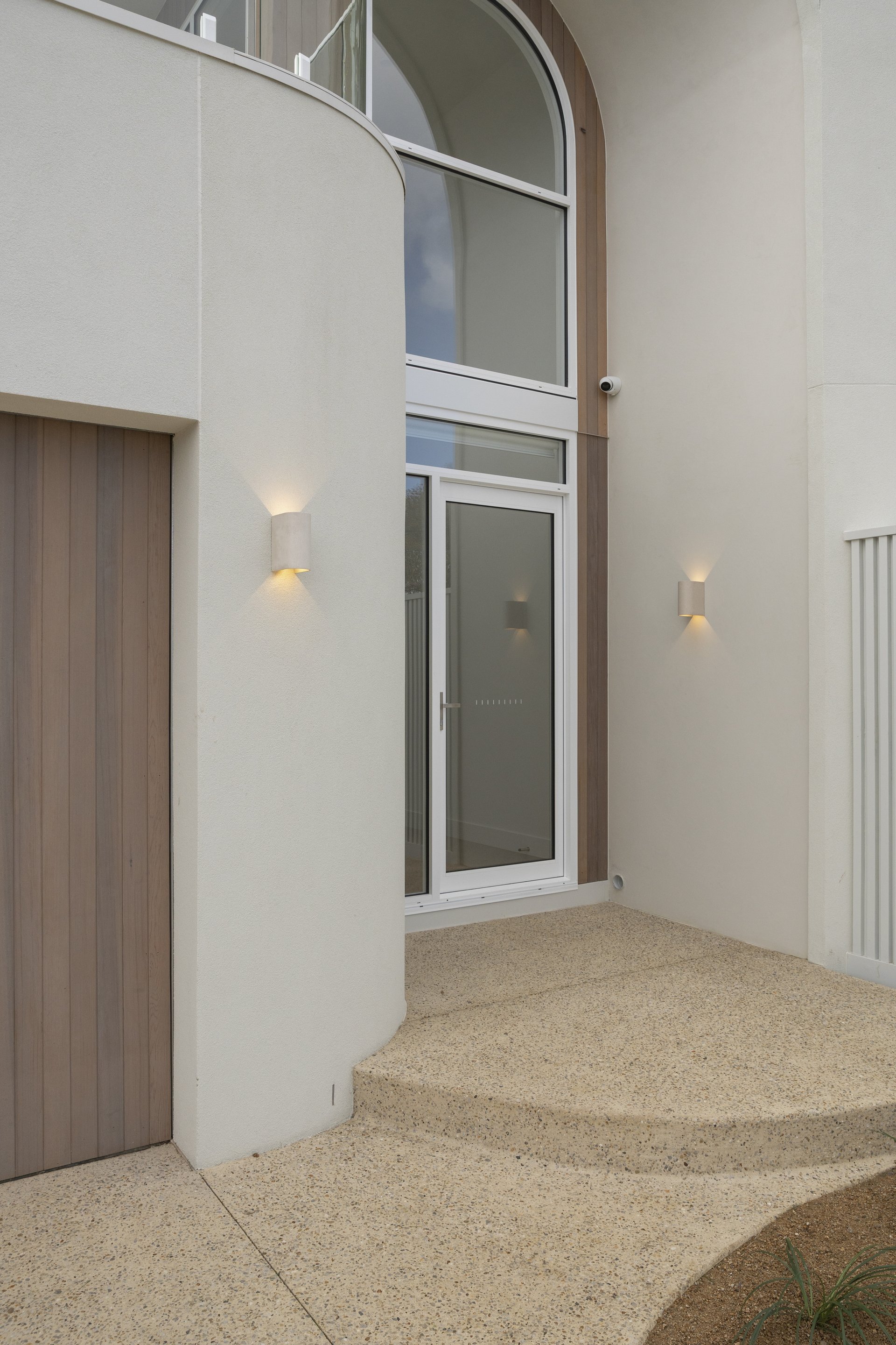 Front entrance with curved portico, aggregate steps and arched glass door