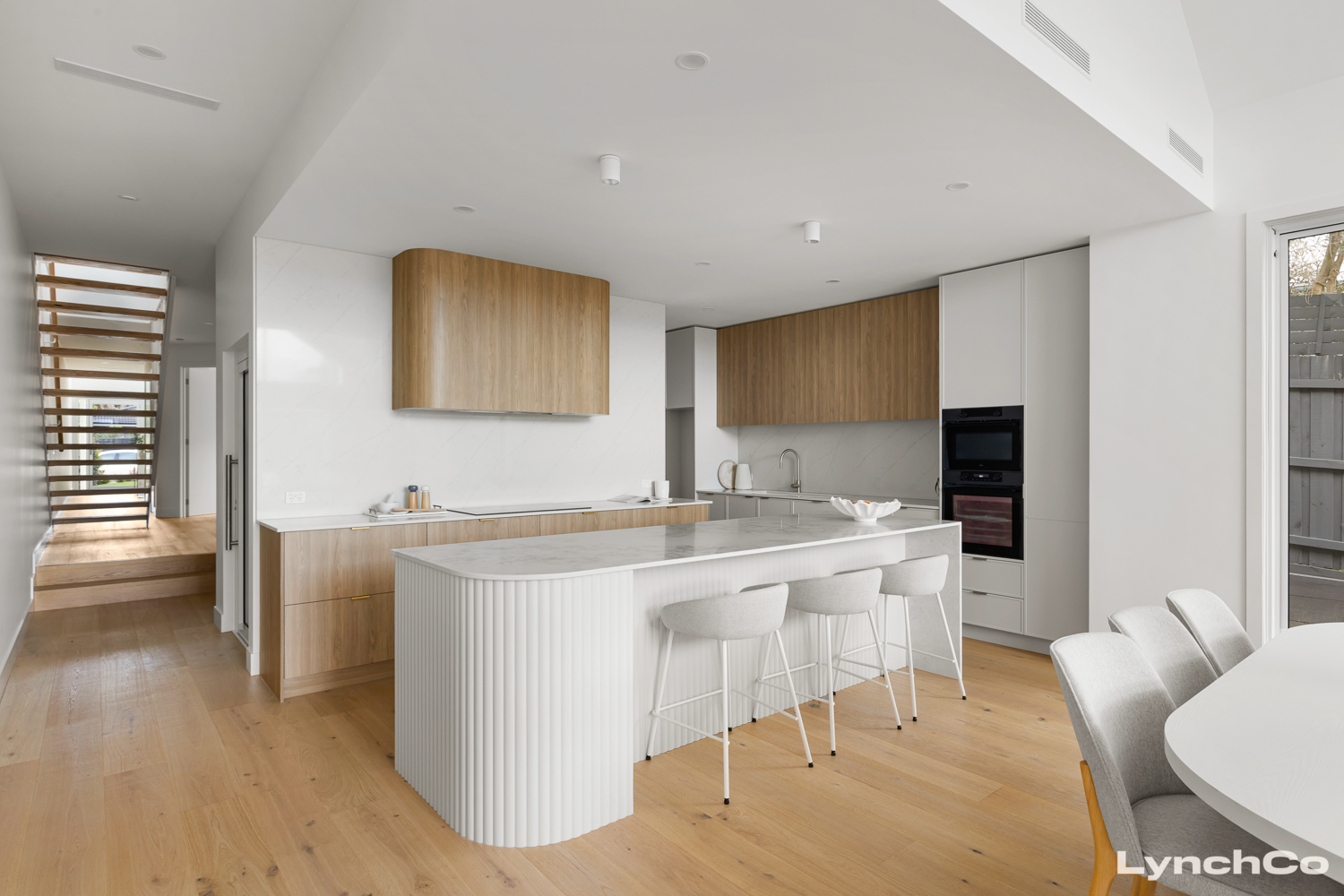 Kitchen with curved marble island and oak cabinetry at 24A Ti-Tree Grove, Mornington